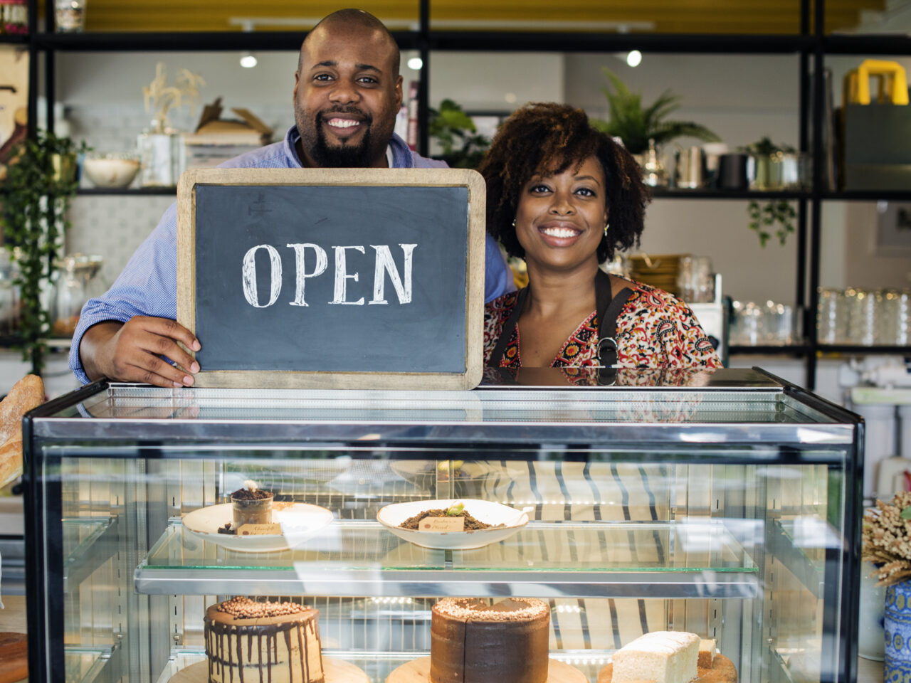 Cake cafe owners with open sign Cake cafe owners with open sign